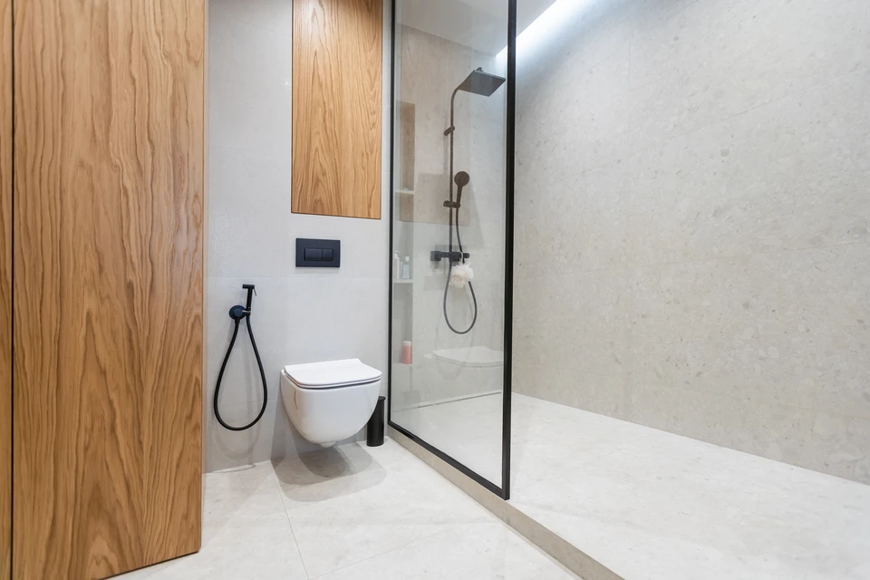 Salle de bain accessible adaptée aux personnes à mobilité réduite avec sanitaires suspendus, barres d'appui inox, lavabo ergonomique et miroir éclairé